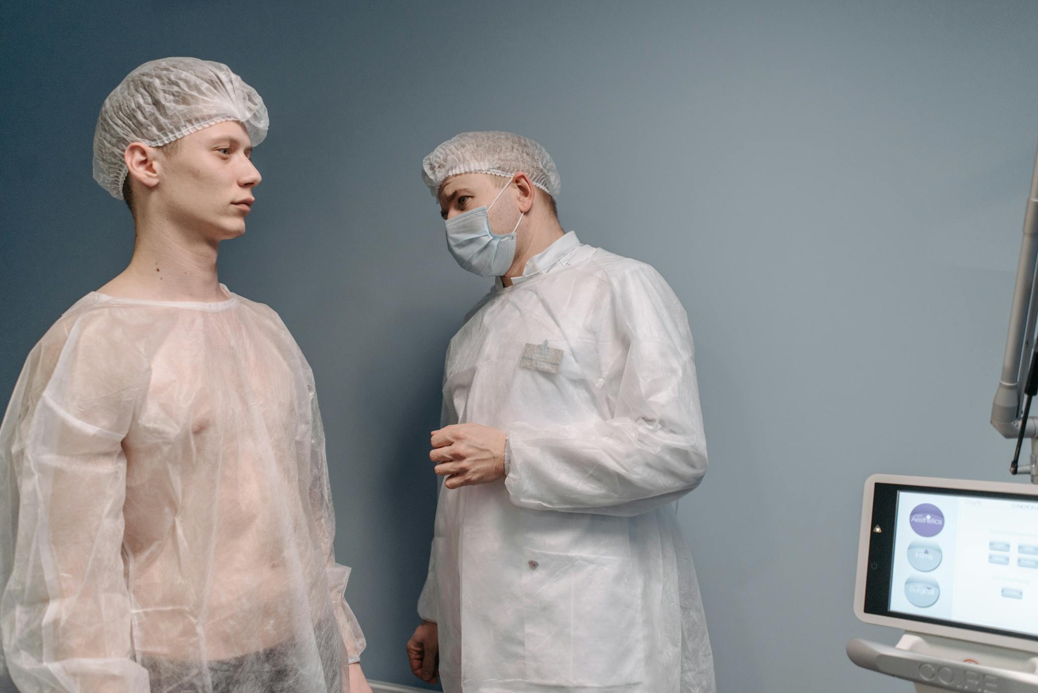 A doctor examines a patient in a clinic wearing medical gowns for a mole pathology evaluation.