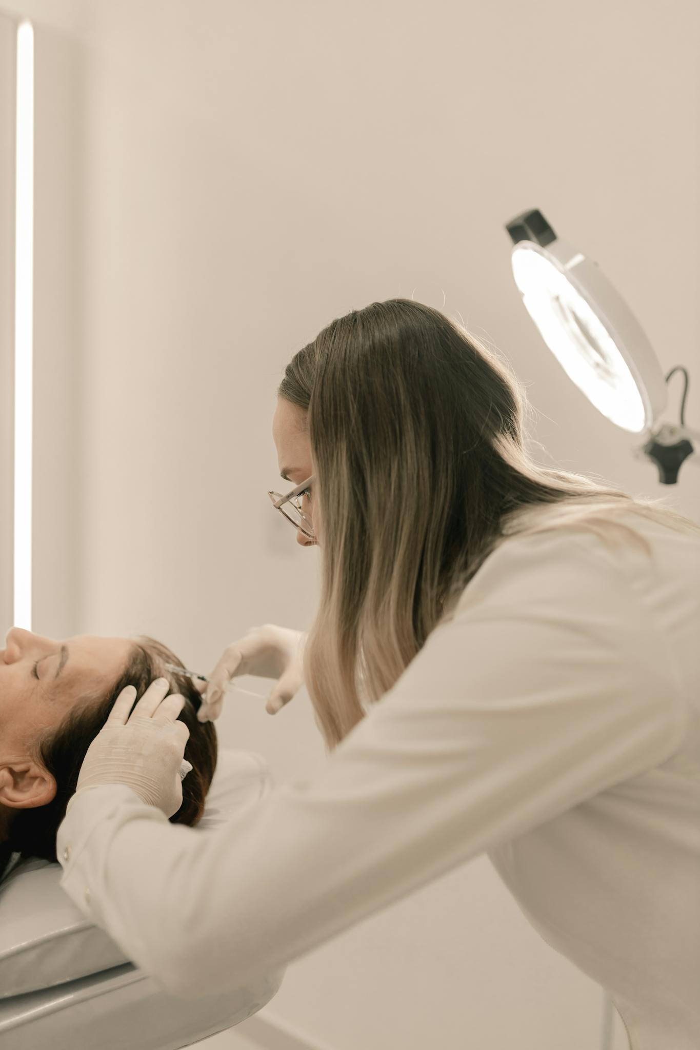 Dermatologist performing a treatment in a clinic setting with specialized equipment.