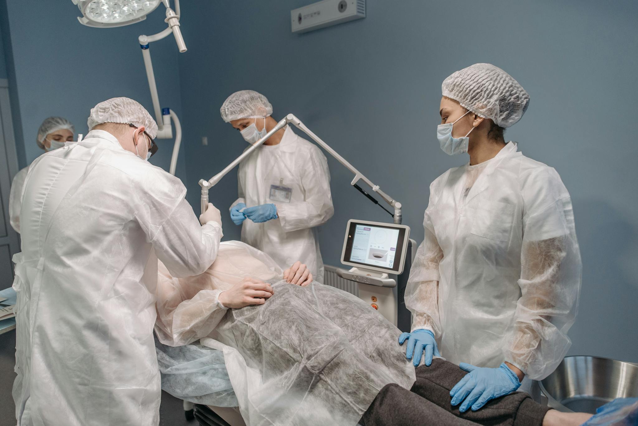 Healthcare professionals conducting a laser surgical procedure in a clinic setting.